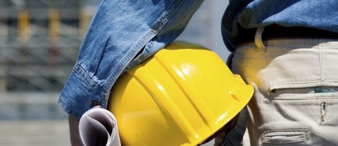 commercial construction worker looking at a project holding a hard hat